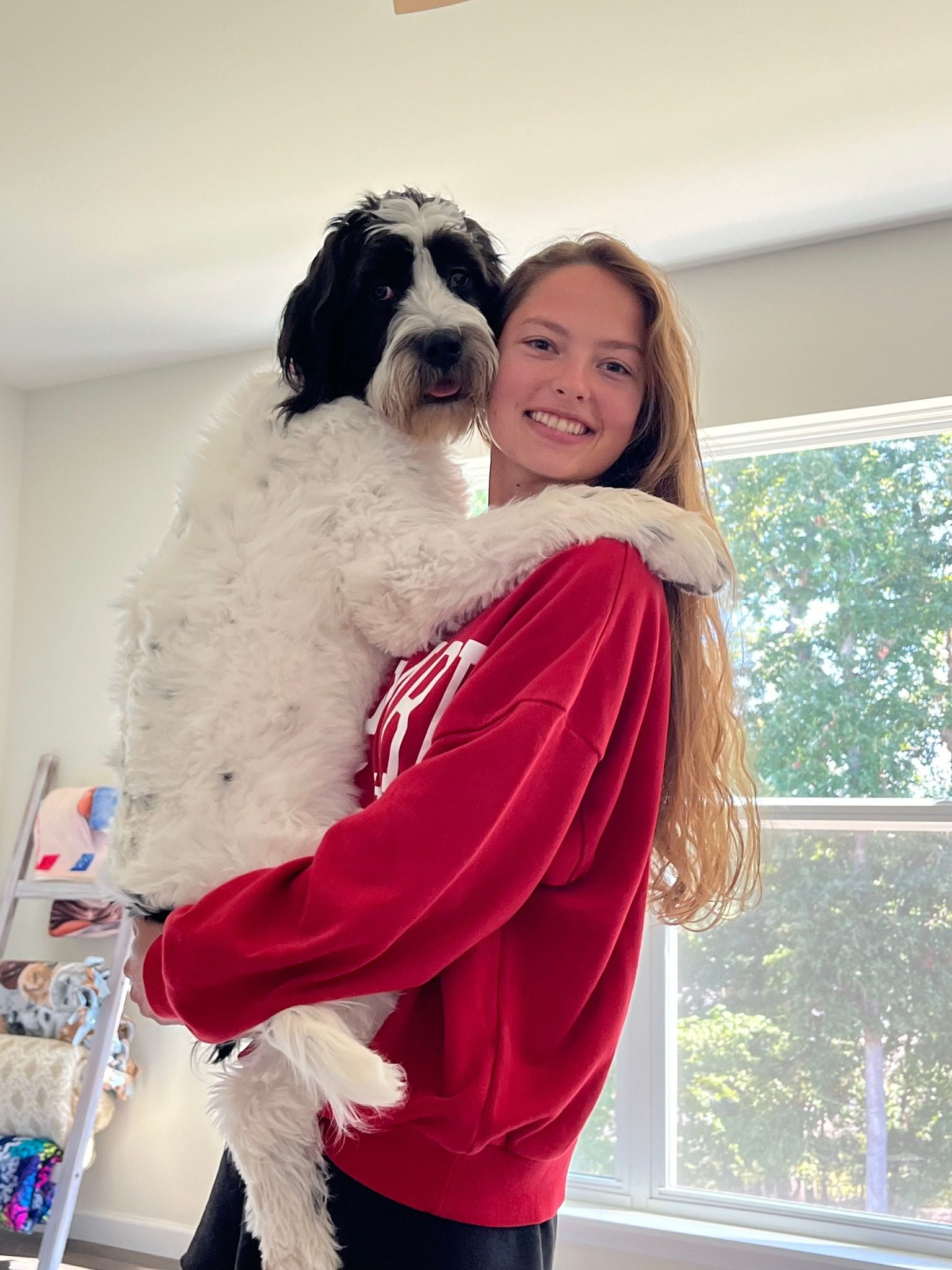 Lauren Macmiller wearing a red sweater and holding her dog