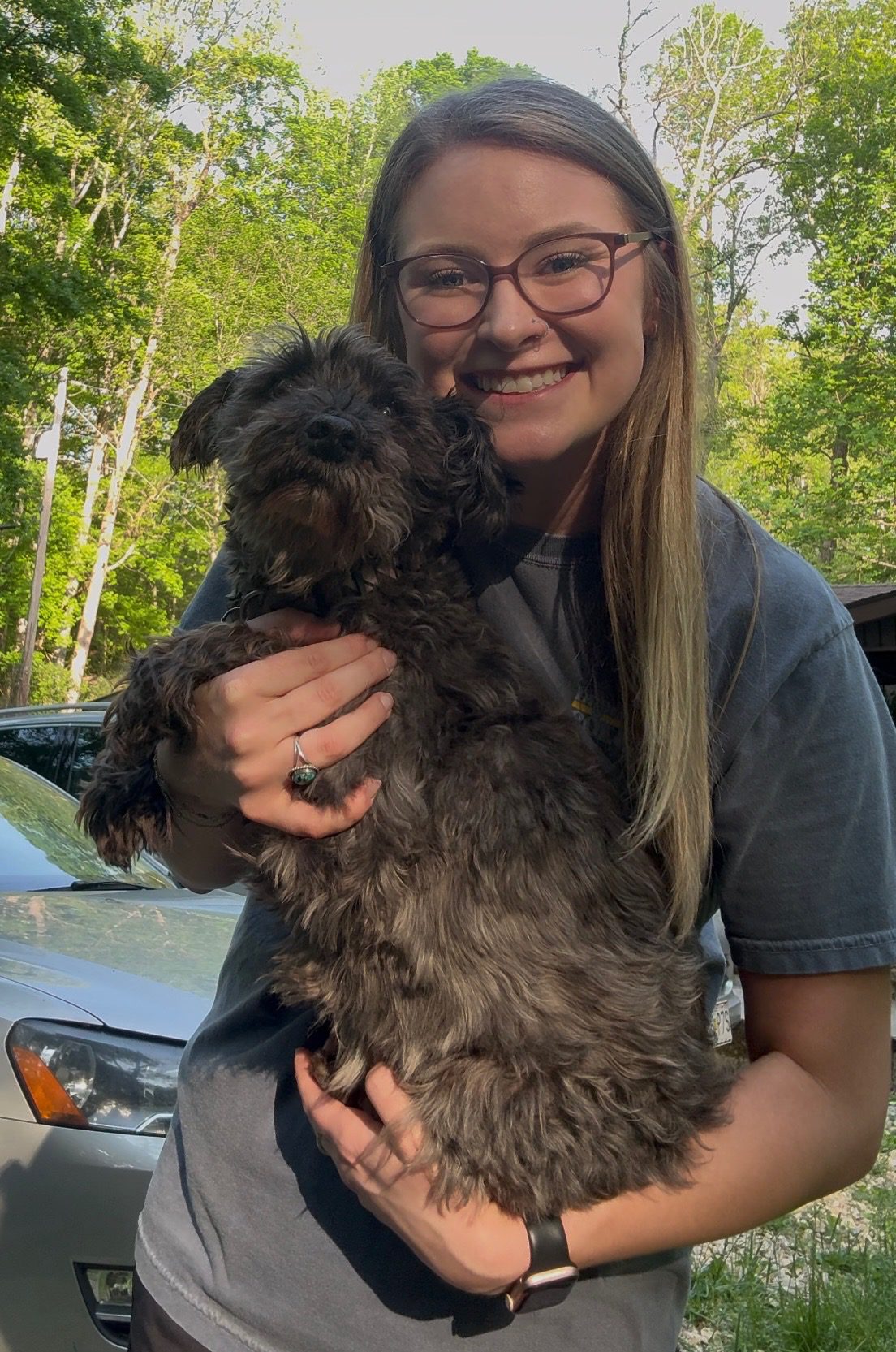lilly standing outside and holding her small back dog