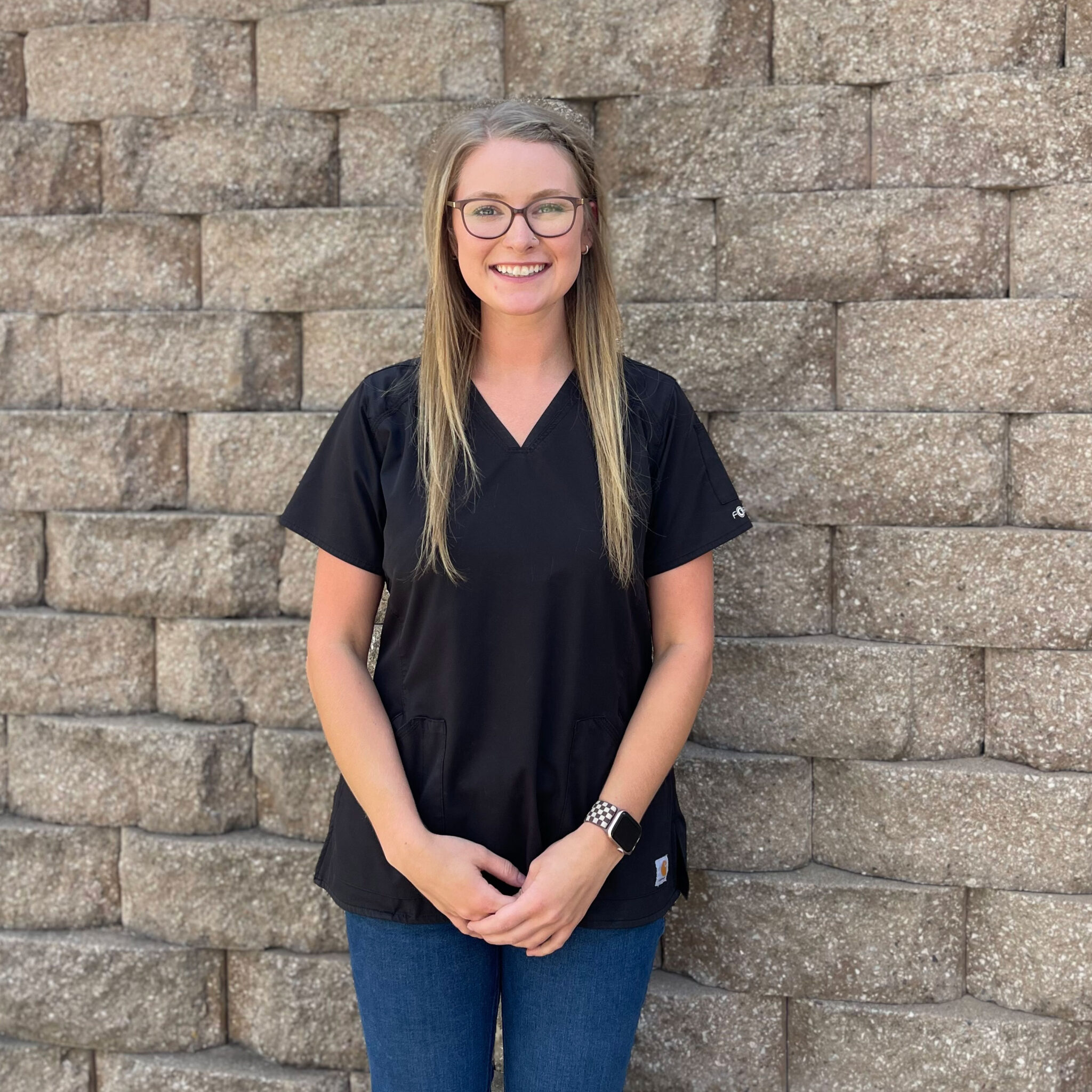 young female veterinary technician assistant smiling in front of brick wall