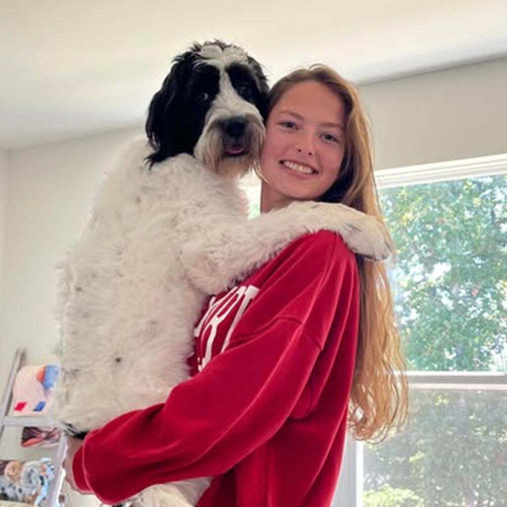Lauren Macmiller wearing a red sweater and holding her dog